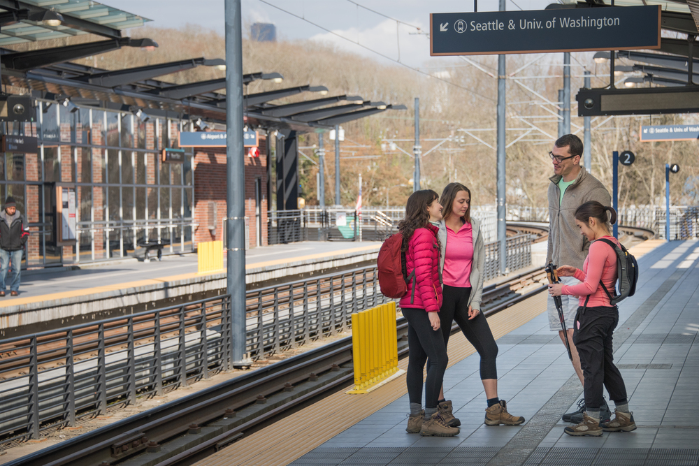 Four adults dressed for hiking waiting on a train platform